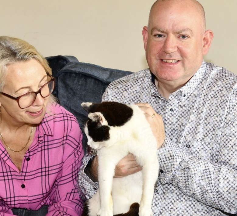 The friendly owners sitting on a sofa with their cat, representing trusted house sitting
